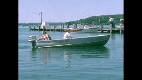 1950s: Boys drive boat across lake, towards dock.