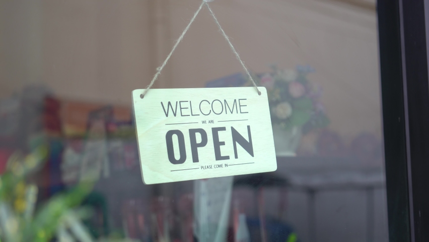 Asian woman wear mask turning Welcome we are open sign on fronton glass door cafe. Reopening activity after COVID-19, ended the lockdown and quarantine. Restarting again and keep forward concept. | Shutterstock HD Video #1060109486