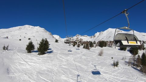 Tonale, Ponte di Legno, Italy, March 5, 2020. Time lapse chairlift with skiers moving to the top of the mountain in a wonderful sunny day