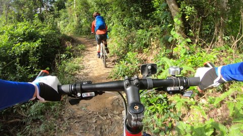 Two friends cross country mountain biking in tropical forest. POV point of view .4k  