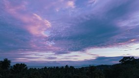 Colorful sky over trees, sea and roof tops on a tropical island at sunset. 4k time lapse