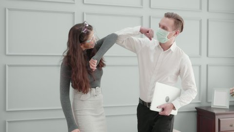 Young american business man in face mask and woman in face shield greeting with elbow bump at office, new normal, male and female meeting and discuss, social distancing, communication concept.