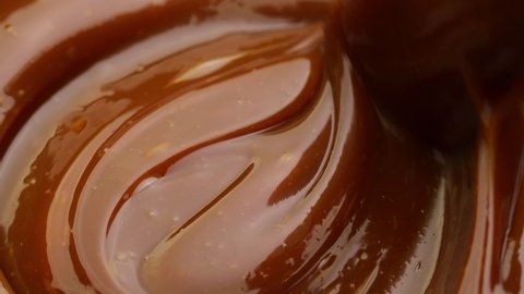 Mixing chocolate cream. Close up of liquid hot chocolate swirl. 