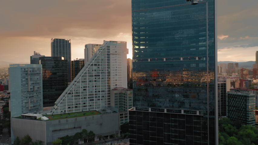 Cinematic view on sunset light and golden clouds over the modern business area in Mexico city. 4K aerial of glass buildings architecture with latin cityscape on motion background. Business offices Royalty-Free Stock Footage #1060137059