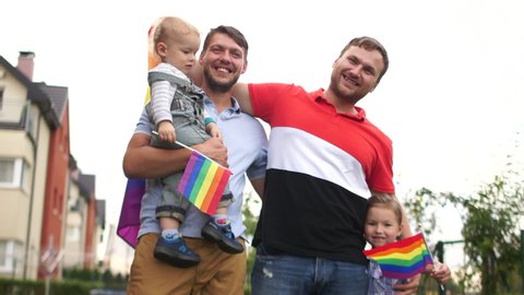 Gay couple. Happy samesex family near their house with flags and two children, a boy and a girl. Gay rights, lgbt community, child adoption, fathers day