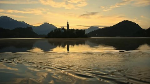 Beautiful golden morning at Lake Bled and Julian Alps in the background. The lake island and charming little church dedicated to the Assumption of Mary are famous tourist attraction in Slovenia