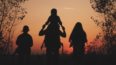 happy family tourists go hiking in park sunset silhouette. adventure travel concept. teamwork. happy family sun a tourists with backpacks hikers go camping. group people teamwork walking park