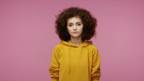 Back off! Disgruntled young woman afro hairstyle in hoodie showing middle finger to camera, expressing disrespect and negativity to haters, gesture of protest. indoor isolated on pink background