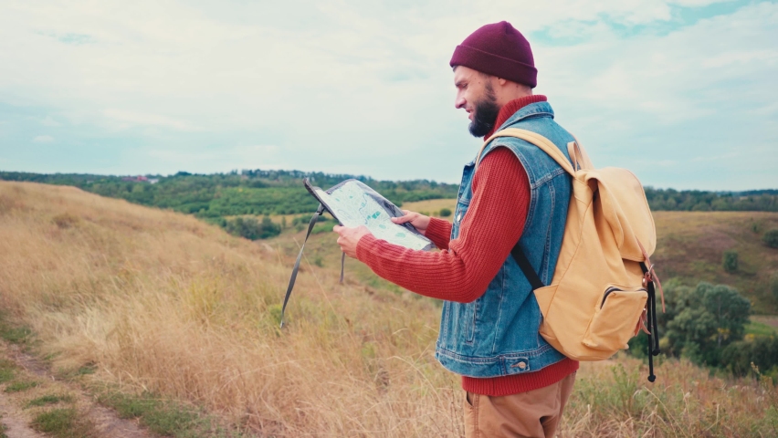 Tourist holding map and walking on hill