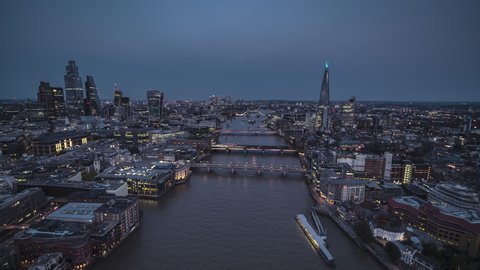 Establishing Aerial View Shot of London UK, London Skyline, City of London & Riverside; Millennium Bridge, Southwark Bridge, London Bridge & Tower Bridge, United Kingdom, night evening