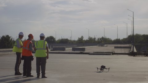 Full body men in uniform launching modern drone while working on bridge construction site
