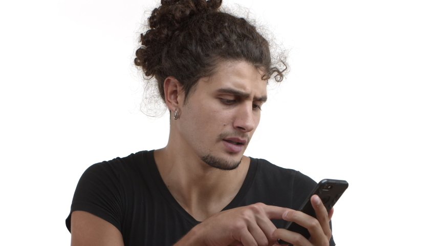 Close-up of serious skeptical handsome man with earring, using mobile phone, swiping left and right, up and down, choosing something in application or online