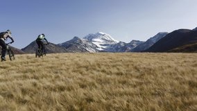 Stunning drone Video of couple riding an E-Bike together in the Mountains of Switzerland - Swiss landscape aerial following footage of two people riding towards a huge mountain