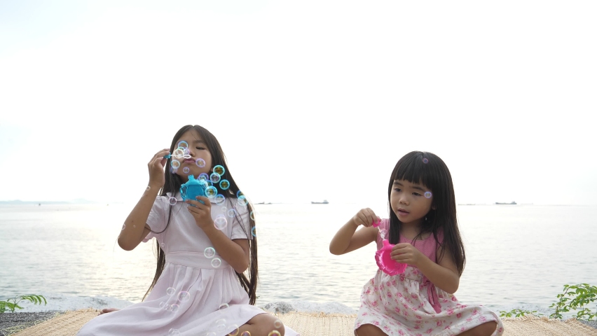 Two sisters little girls inflate soap bubbles on a picnic in a field in the spring. the concept of travel and outdoor leisure.