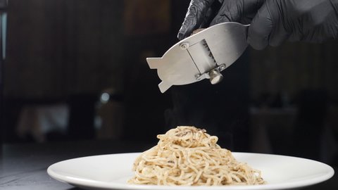 Chef grates black truffle on pasta in Italian restaurant. Slow motion. Concept of gourmet cuisine, truffles, Italian pasta, fine dishes. Delicious Italian fettuccine with black truffle on top. Full hd