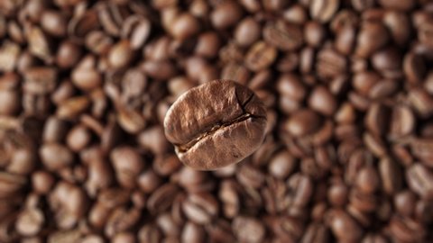 Super slow motion macro shot of flying coffee bean against rotating background of freshly roasted coffee.