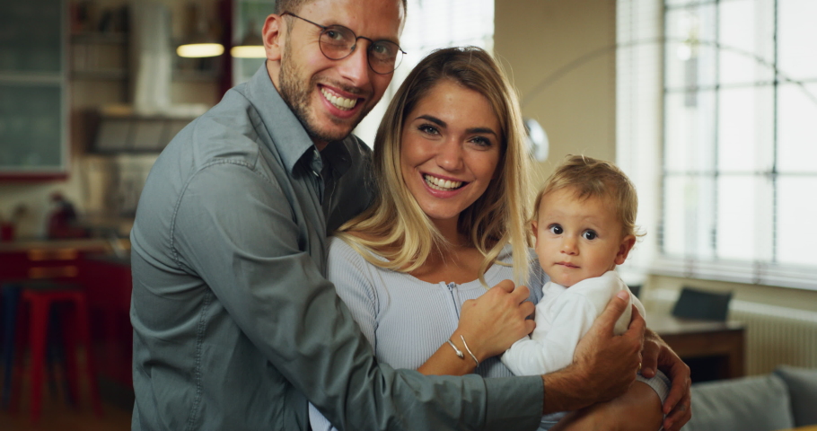 Authentic shot of a young happy family with toddler baby boy are smiling in camera in a kitchen at home. | Shutterstock HD Video #1060179215