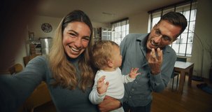 A happy smiling family with toddler baby boy is making a selfie or video call to friends or relatives while having a breakfast together in a living room at home.