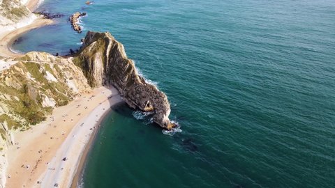 Aerial drone shot tracking around to reveal the famous Durdle Door rock formation on the jurassic coast in Dorset.