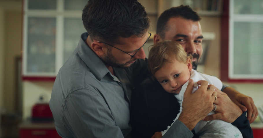 Authentic shot of young happy homosexual male gay family with adopted son toddler baby boy is smiling in camera in a kitchen at home. | Shutterstock HD Video #1060180076