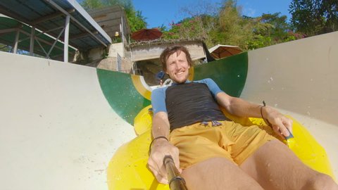 A young man rides on an inflatable circle in a slide in the aqua park. In the middle of a tube, he falls from a circle and hits the wall. Injuries in water parks