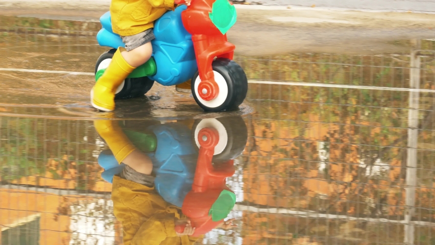 A toddler with rubber boots playing in the puddles