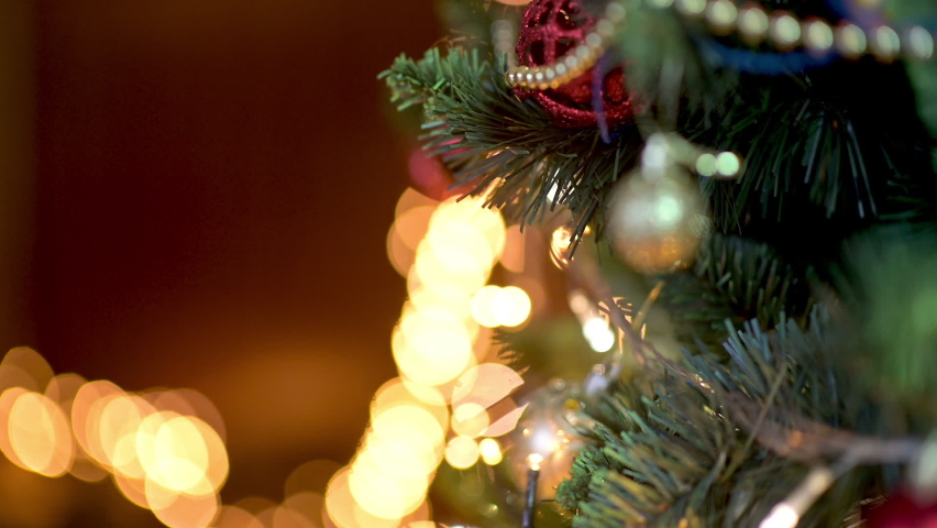 Close-up of kid's hands decorating Christmas tree with balls on the background of bright festive lights. children decorating a Christmas tree. Royalty-Free Stock Footage #1060182365