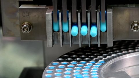 Close up Blue capsule medicine pill production line, Industrial pharmaceutical concept.