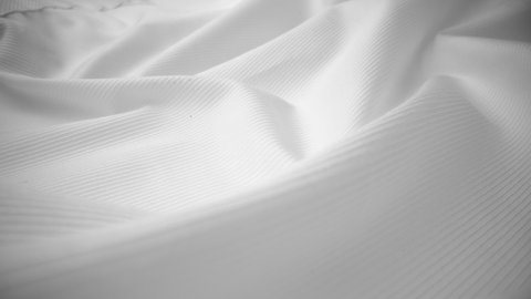 Shiny flowing cloth texture dolly shot in close up view macro shot. Wavy clean silk weave material. Textile abstract background. Bed sheet, curtain and clothing industry concept.