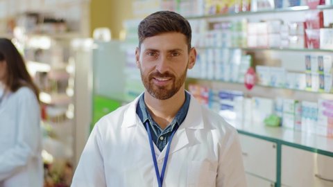 Portrait of handsome caucasian smiling man apothecarist looking into camera. Adult bearded pharmacist at work. Medical sector, doctor and health care concepts.