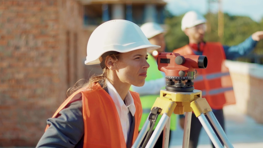 Close up young woman surveyor in work clothes and helmet takes measures with theodolite stand helmet hardhat geodesy digital engineering real estate teamwork infrastructure industry slow motion Royalty-Free Stock Footage #1060193960