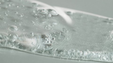 Crystal Clear Gel With Bubbles Flowing On A White Surface. - macro shot