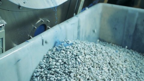 Slow motion shot of pumice stones pouring from industrial washing machine in jeans factory. close up.
