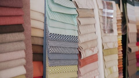 Various Fabrics Hang in Multiple Colors and Patters off a Wall, Camera Tilt down