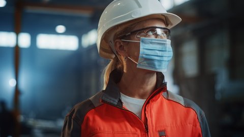 Portrait of a Professional Heavy Industry Engineer/Worker Wearing on Safety Face Mask in a Steel Factory. Beautiful Female Industrial Specialist in Hard Hat Standing in Metal Construction Facility.