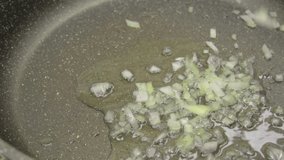 Video of pouring fresh chopped onions into a frying pan with oil. Cooking, vegan food