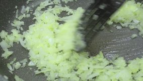 4K video of mixing and cooking fresh chopped onions in a pan with oil with a spatula. Cooking, vegan food