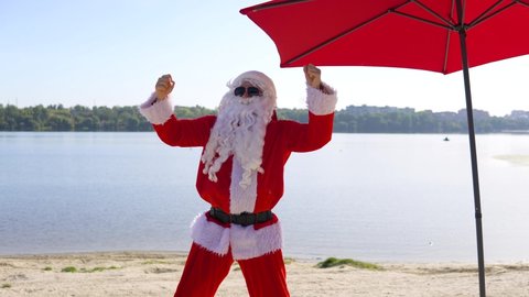 Santa Claus is having fun and dancing in club style on the beach. Christmas vacation