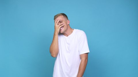 Young caucasian man blink at the camera through fingers, embarrassed covering face
