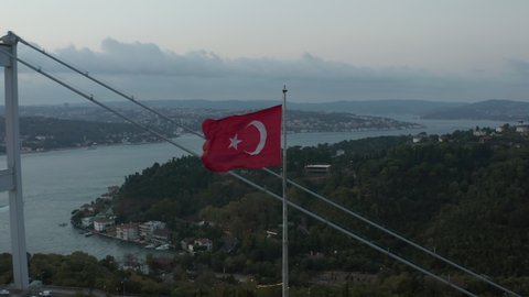Turkish Flag Waving in Wind in front of Istanbul Bosphorus Bridge, Aerial medium shot slide right