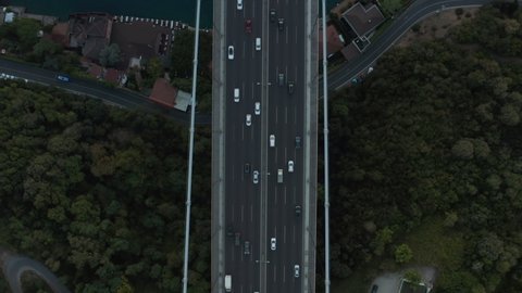 Cars driving on Big Bridge surrounded by Trees onto River in Istanbul, Incredible Birds Eye Aerial View forward 