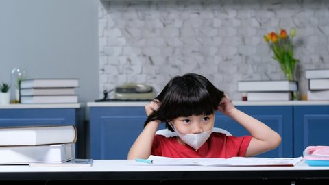 Girl wearing protect mask and doing homework, child writing paper,  education concept, back to school