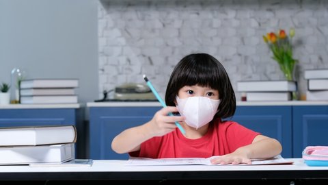 Girl wearing protect mask and doing homework, child writing paper,  education concept, back to school
