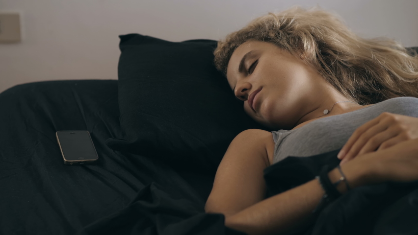  rude awakening -  a phone call wakes up a young sleeping woman Royalty-Free Stock Footage #1060224311