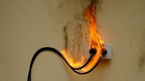 On fire electric wire plug peceptacle on the concrete wall exposed concrete background