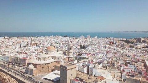 Aerial perspective of Cathedral of Cadiz. Drone passing close to the Cathedral Tower. Beautiful Baroque details of the cathedral and church. Drone going backward. Roof of Cadiz. Panorama over city. 