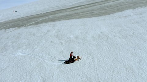 Aerial view of a tourist enjoying riding his snowscooter on steep mountains of snow capped Icelandic glacier.