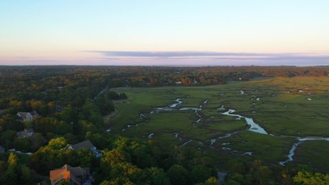 Cape Cod Bay Aerial Drone Footage of Houses, Marsh, Tall Green Grass and Water Creeks at Golden Hour Surrounded by Trees