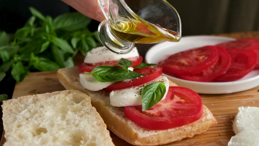 Slow motion olive oil pouring on caprese panini sandwich. Italian food