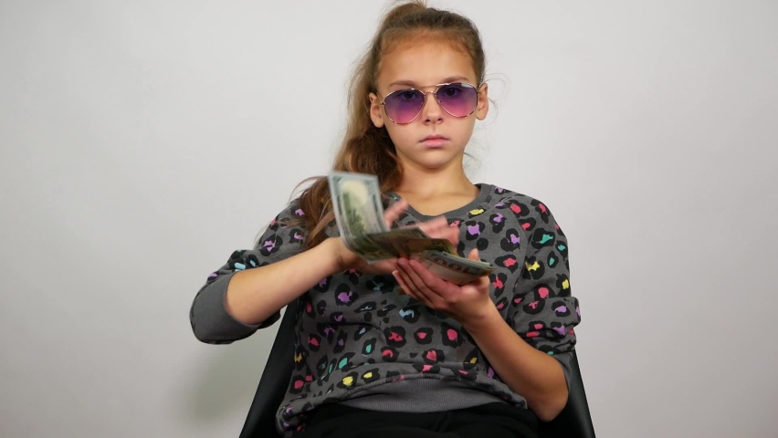 Imperturbable young girl sitting in a chair and throwing money. Big boss | Shutterstock HD Video #1060232294